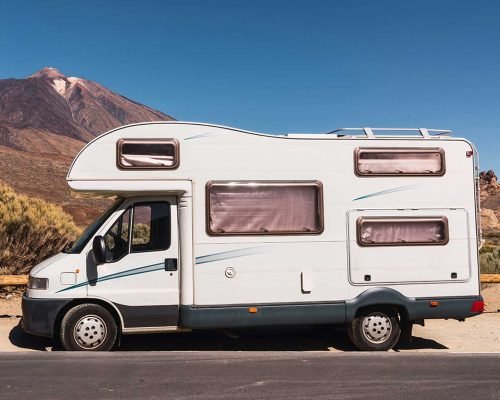 camper-van-on-road-near-hill-and-blue-sky-2021-12-09-12-34-12-utc